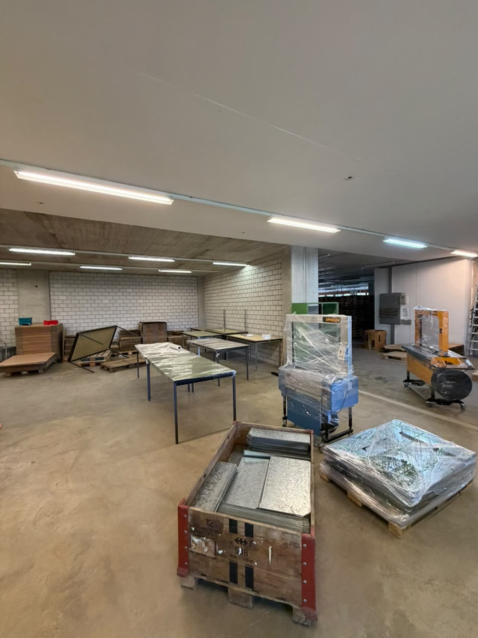 Geleerte Lagerhalle mit Paletten und zusammengelegten Regalen nach der Räumung